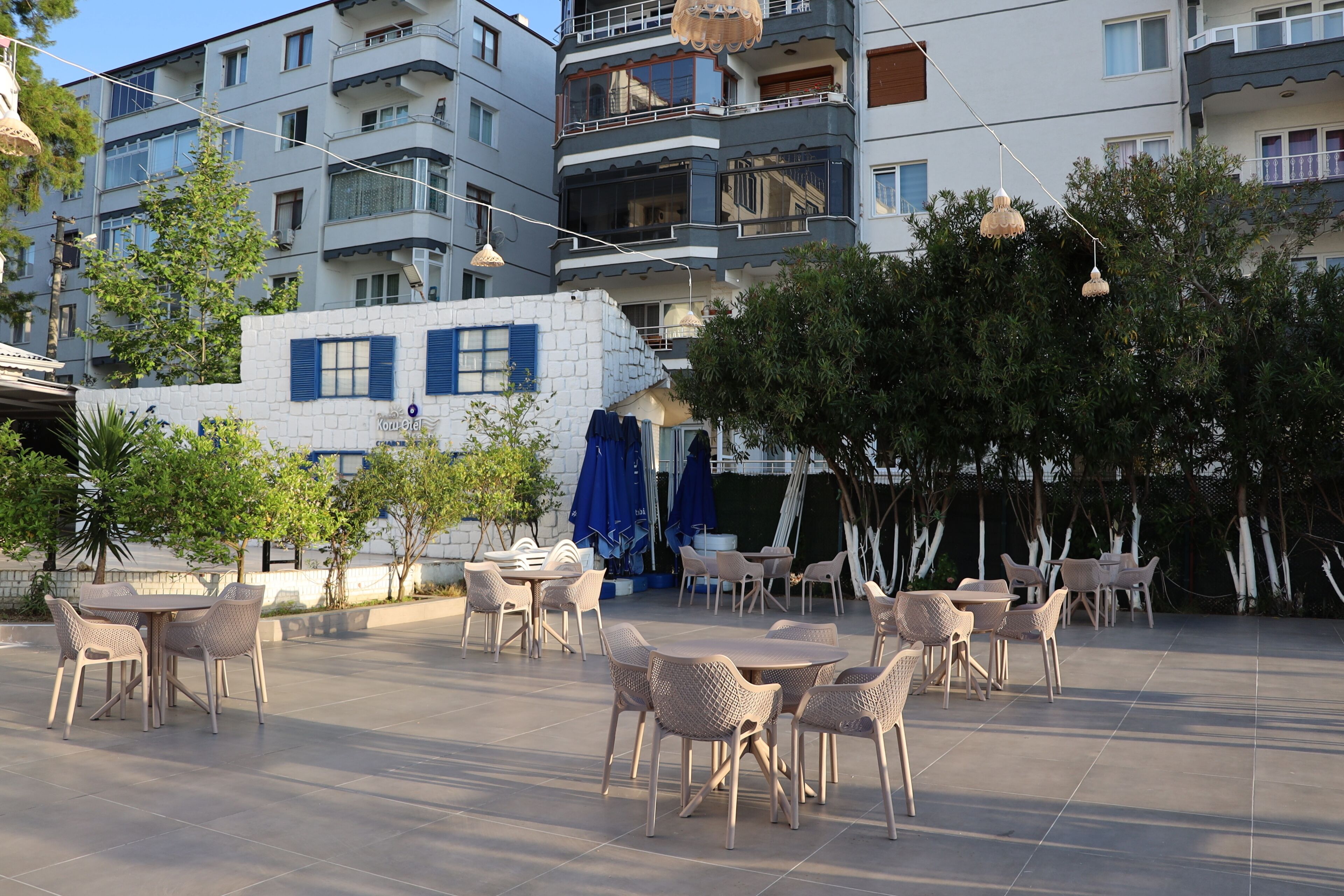 An outdoor seating area with tables and chairs, surrounded by buildings and trees.