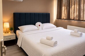 A hotel room with a large bed, a bedside table with a lamp, and a window with curtains. - Grand Koru Otel Beach (Cinarcik)