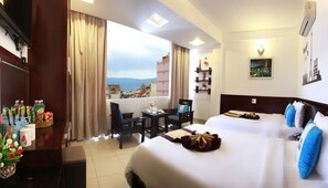 Camera d'albergo con un letto grande, una scrivania e una sedia. Si vede la città dalla finestra.