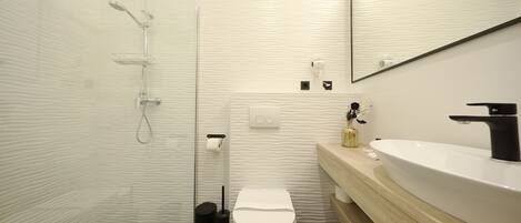 A modern bathroom with a shower, toilet, and sink.