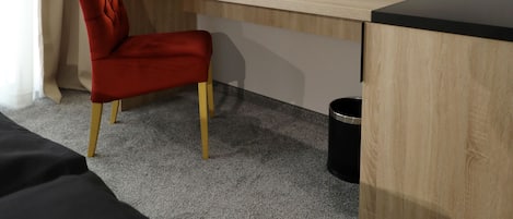 Una habitación de hotel con cama, escritorio, silla, televisión y lámpara.