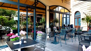 Un espace extérieur aménagé avec des tables et des chaises, une partie couverte avec un plafond en bois, et une enseigne indiquant le Teatro Verdi Boutique Hotel.