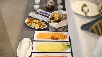 A buffet table with various food items including fruits, pastries, and condiments.