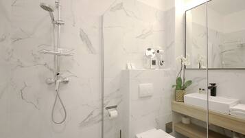 A modern bathroom with a glass shower enclosure, a white toilet, a sink with a mirror, and marble-patterned walls.