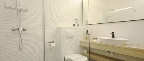 Un baño moderno con cabina de ducha de vidrio, inodoro blanco y tocador de madera con espejo.