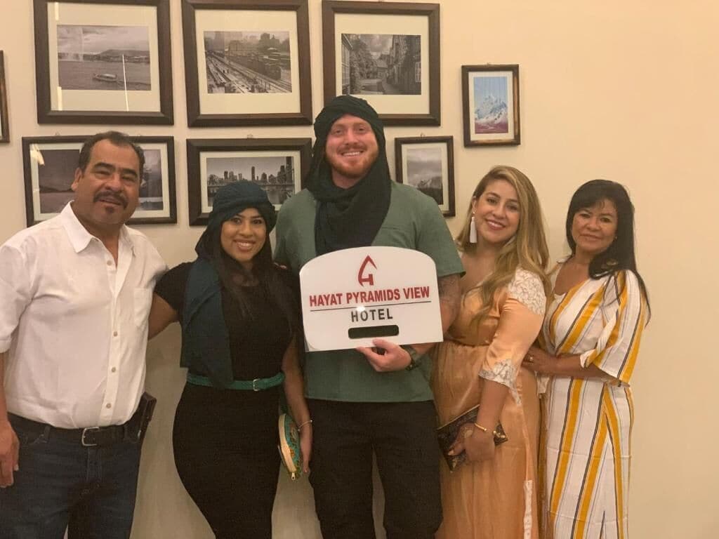 Eine Gruppe von Personen hält ein Schild für das Hayat Pyramids View Hotel.