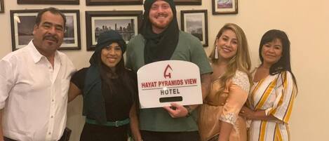 Eine Gruppe von Personen hält ein Schild für das Hayat Pyramids View Hotel.