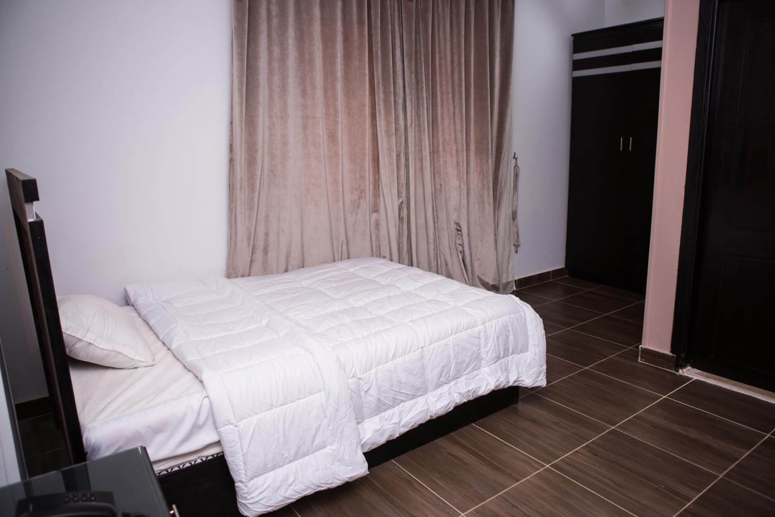 A bedroom with a bed, a wardrobe, and a curtain.
