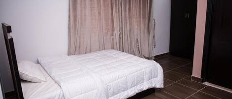 A bedroom with a bed, a wardrobe, and a curtain.