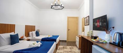 Una habitación de hotel con dos camas, un minibar, un televisor y una puerta.