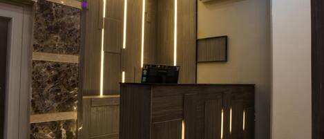 A reception area with a marble wall, wooden paneling, and a reception desk.