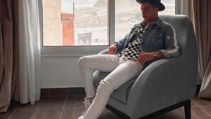 Un hombre sentado en un sillón moderno junto a un ventanal con vista a una pirámide.