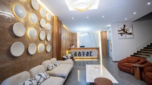 Un moderno vestíbulo de hotel con mostrador de recepción, sofás y una escalera.