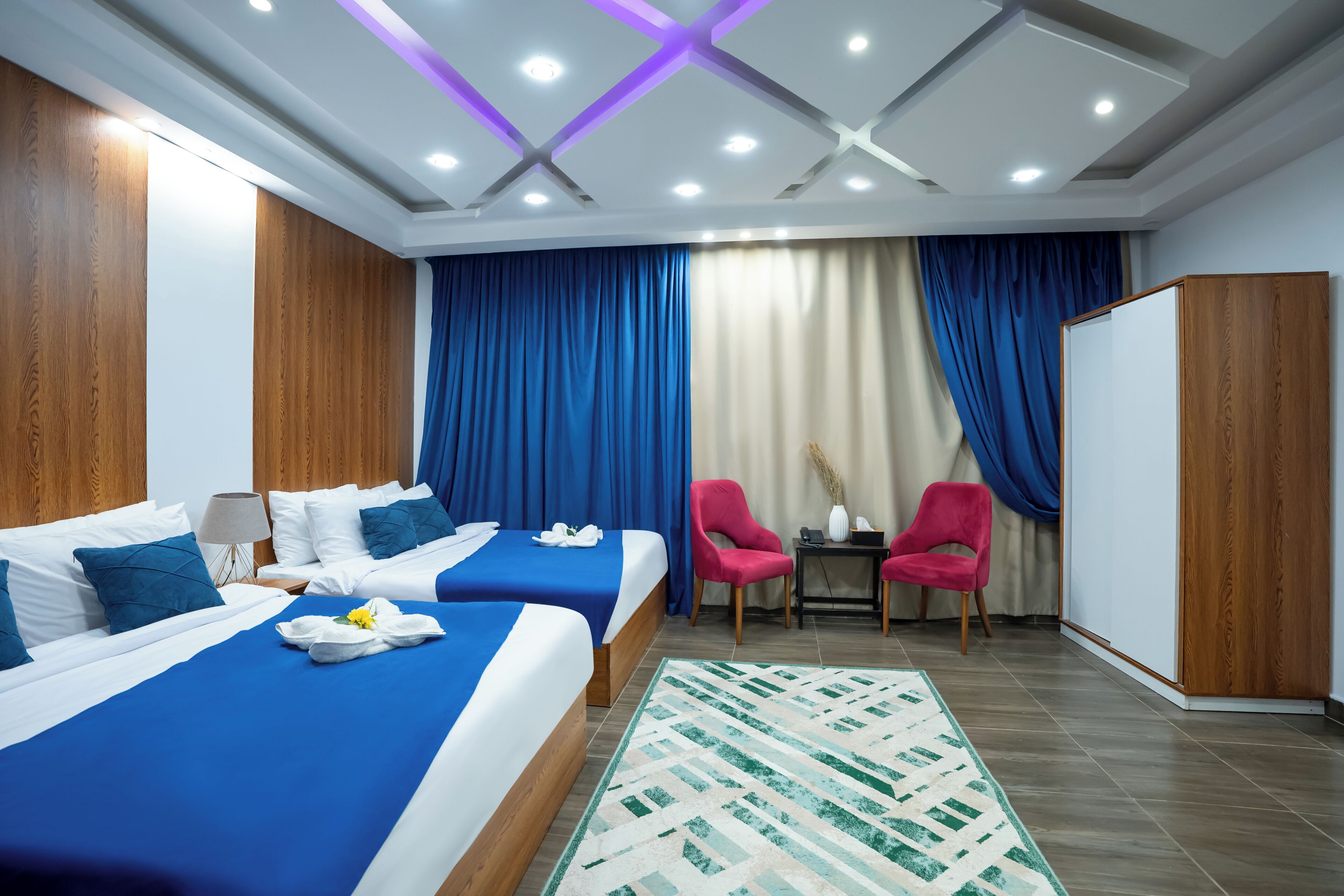 Habitació d'hotel amb dos llits, una taula de treball, una cadira i un armari.