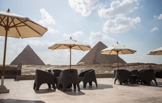 Outdoor seating with umbrellas and views of pyramids.