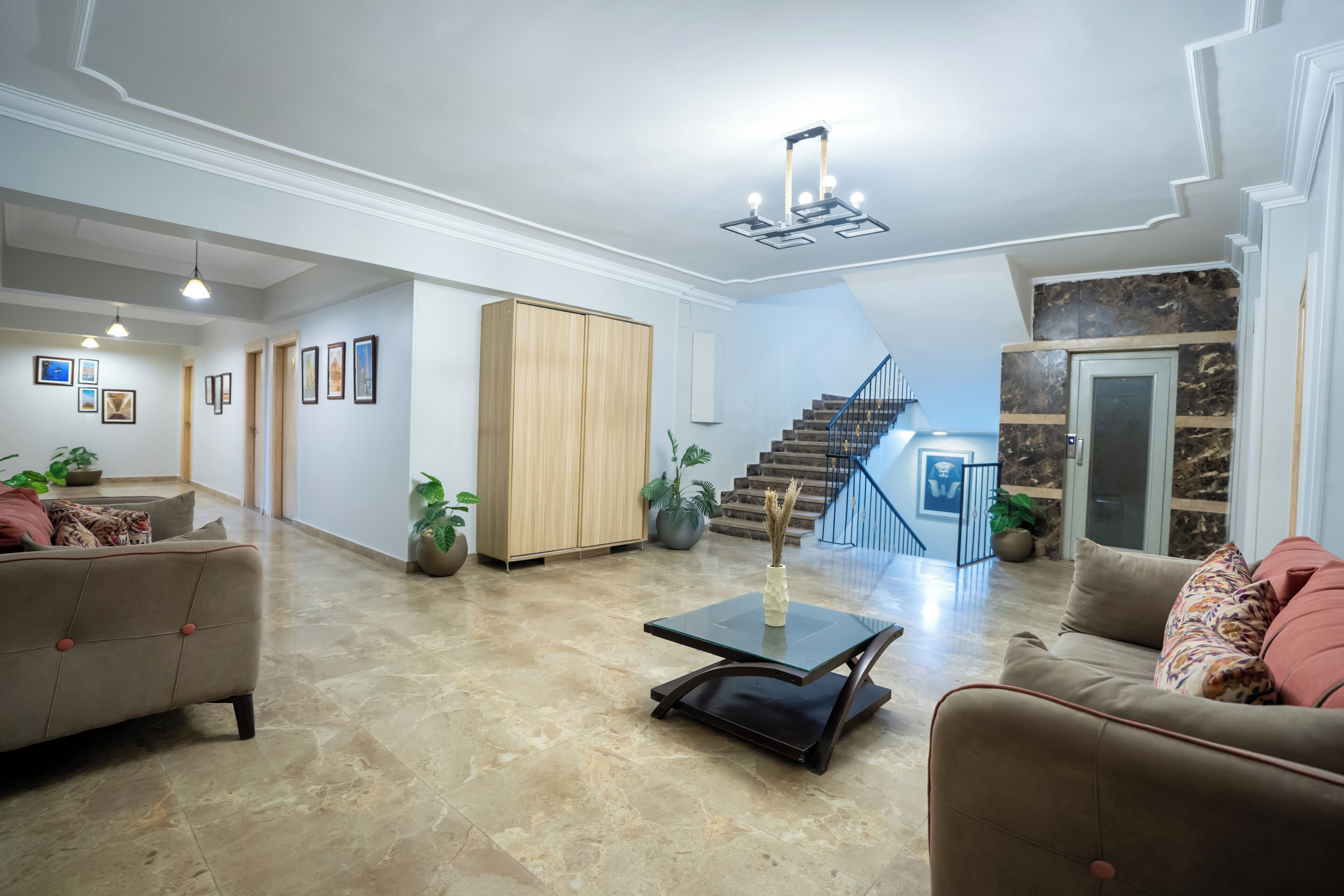 A spacious living room with a high ceiling, a staircase, and a view of the outside.