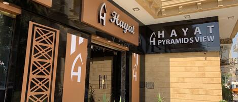 L’entrée d’un hôtel, avec une enseigne indiquant « A HAYAT, vue sur les pyramides ».