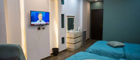 A hotel room with two beds, a TV on the wall, a small desk, and a wardrobe.