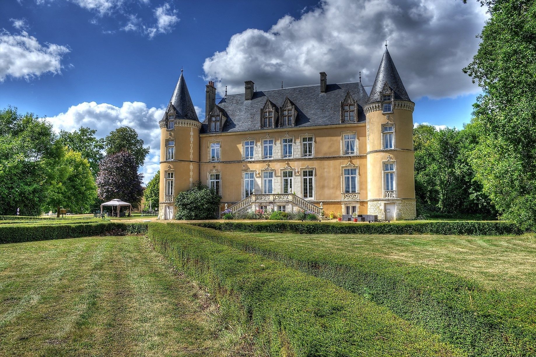 Un grand bâtiment historique doté de nombreuses tours et d’un jardin bien entretenu.
