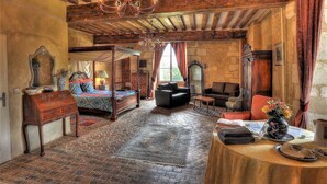 Een ruime kamer met een groot bed, een zithoek met banken en een eettafel.