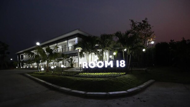 A modern building with a sign that reads "ROOM 18" illuminated at night.