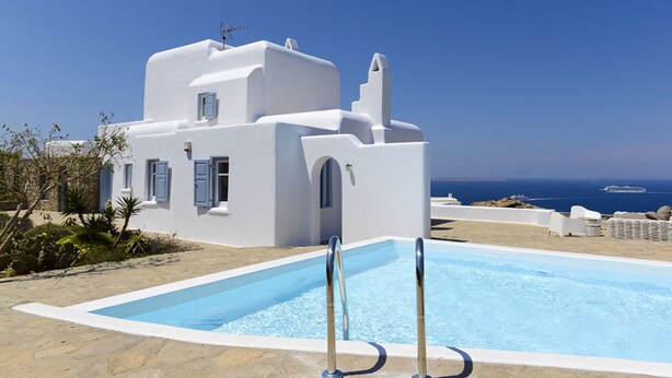 Un edificio blanco con piscina, rodeado de un cielo azul cristalino y el mar.