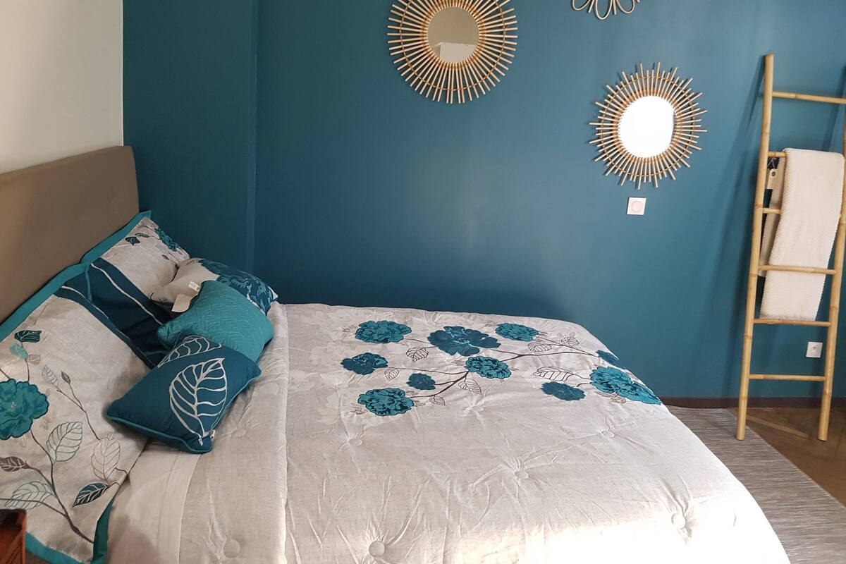 A bedroom with a bed, a ladder, and three wall-mounted mirrors.