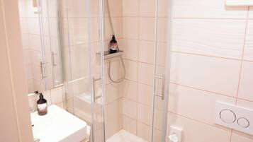 A modern bathroom with a glass-enclosed shower, a white sink, and a toilet.