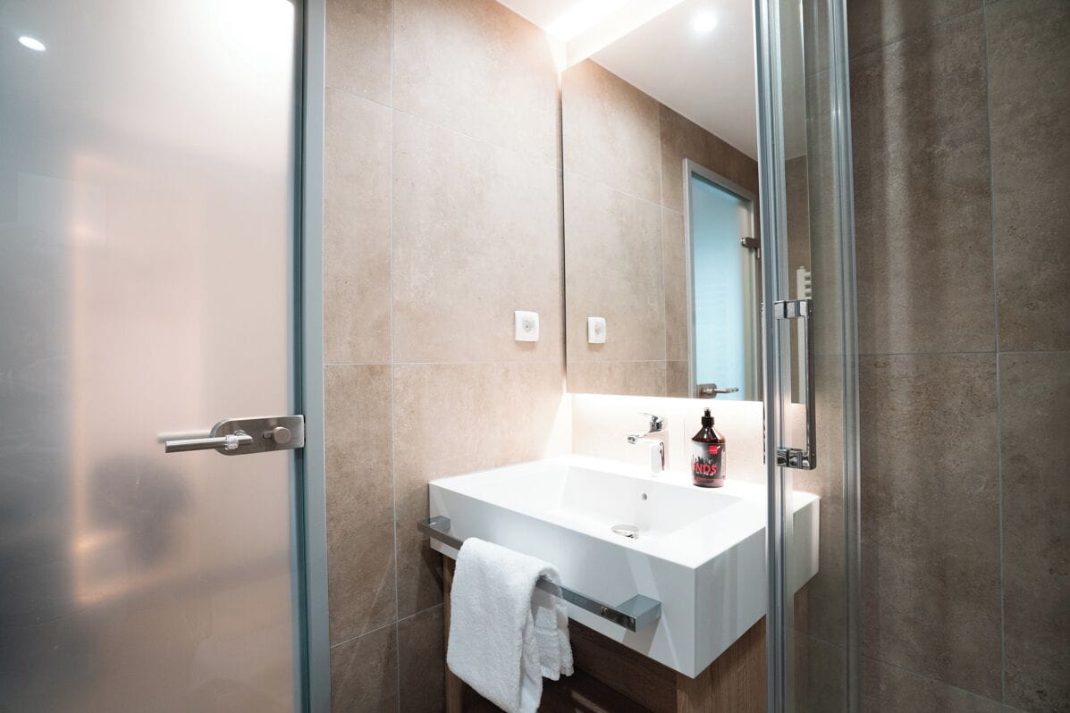Une salle de bain moderne avec une douche à parois de verre, un lavabo blanc et un miroir.