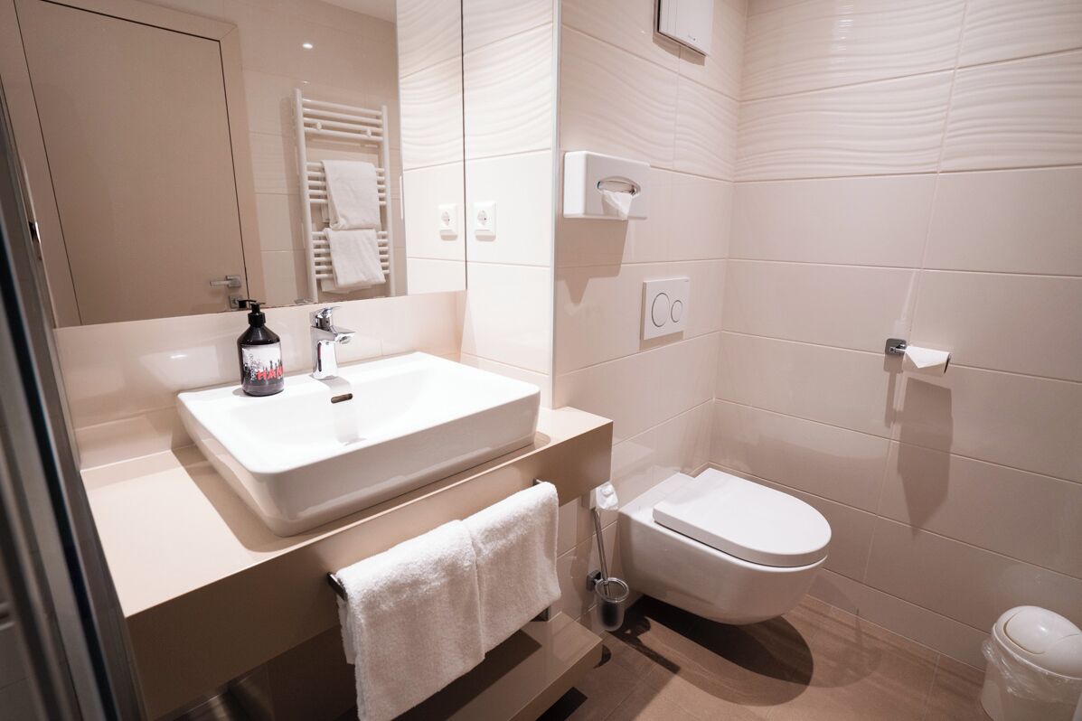 A modern bathroom with a white sink, a toilet, and a towel rack.
