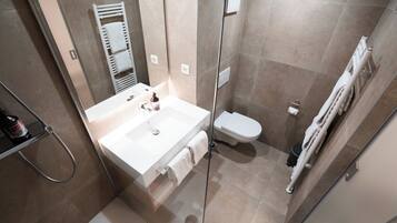 Un baño moderno con cabina de ducha de vidrio, un lavamanos blanco y un inodoro.