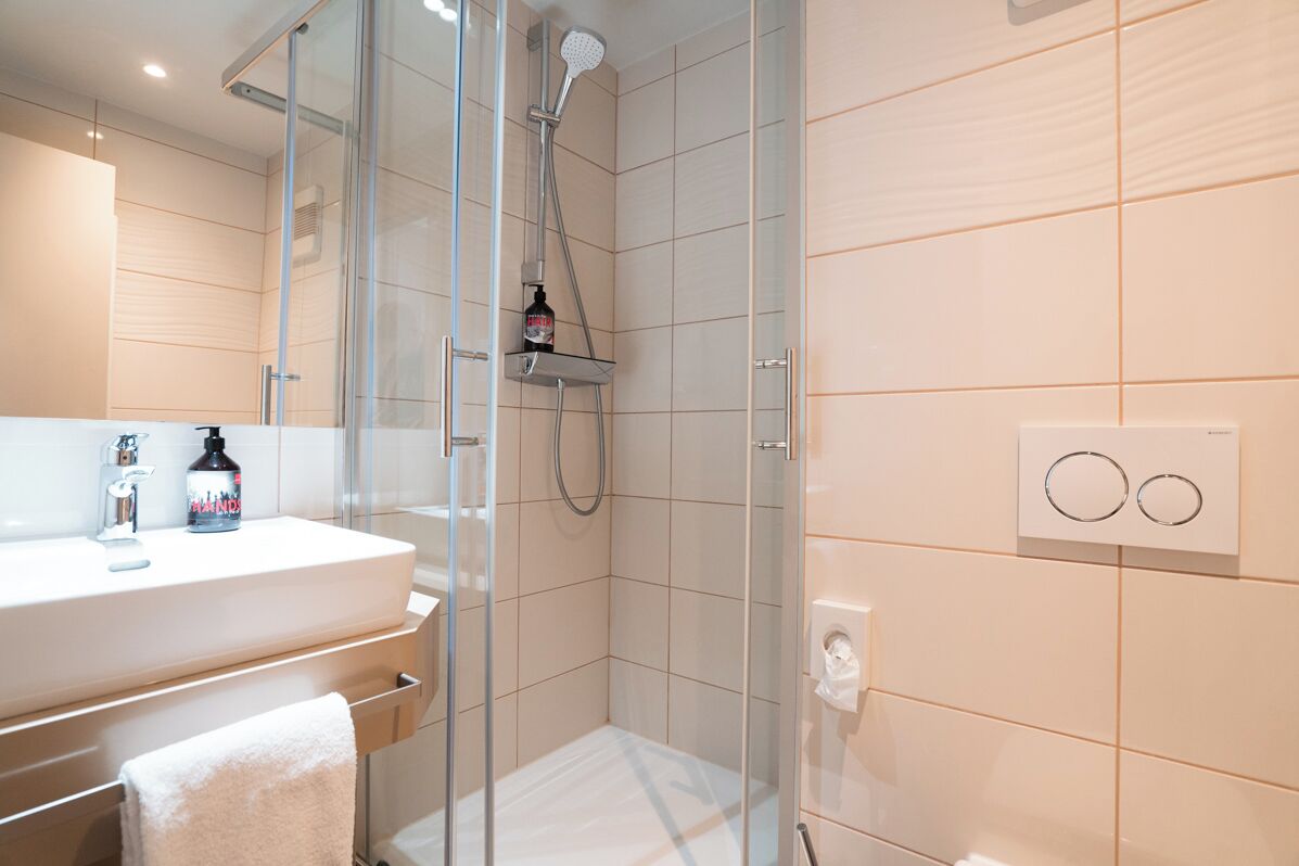 Un bagno moderno con box doccia in vetro, lavandino bianco e portasciugamani.