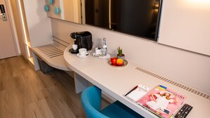 Eine moderne Küchenzeile mit Kaffeemaschine, Tassen, einer kleinen Pflanze und einer Zeitschrift auf der Arbeitsfläche.