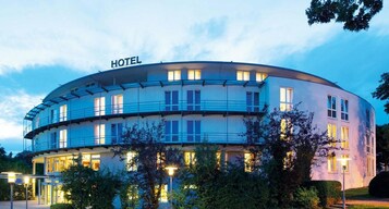 Um hotel moderno com fachada curva, várias varandas e entrada bem iluminada.