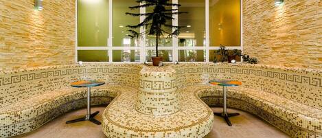 Un área de spa con asientos de mosaicos, una planta central y un ventanal grande.