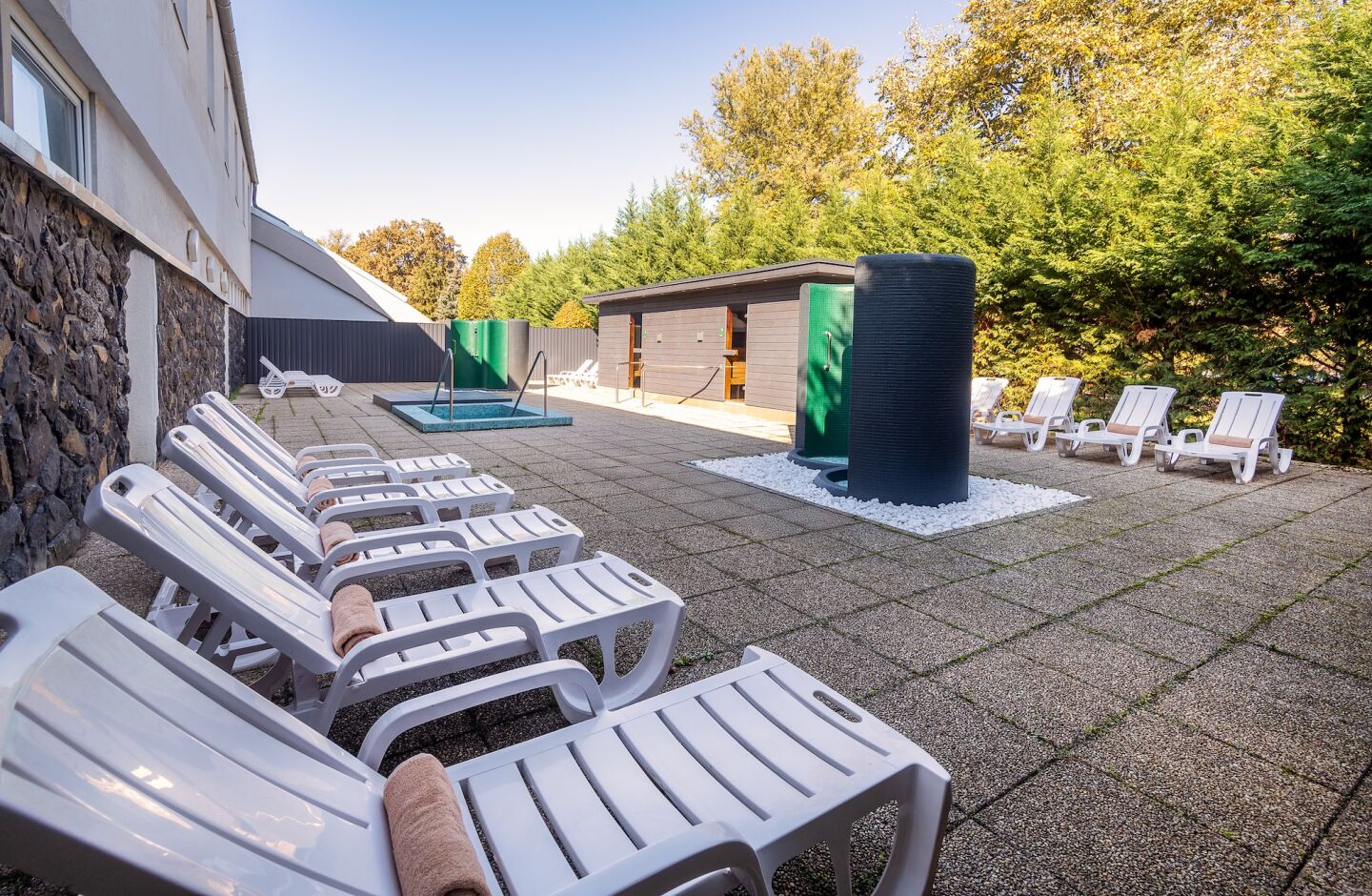 Un espace spa comprenant des chaises longues blanches, une petite piscine et un sauna.