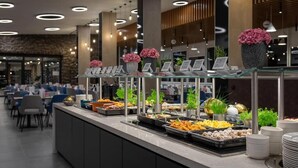 A buffet area with various food options and a seating area with chairs and tables. - Hunguest Hotel Apollo (Hajduszoboszlo)