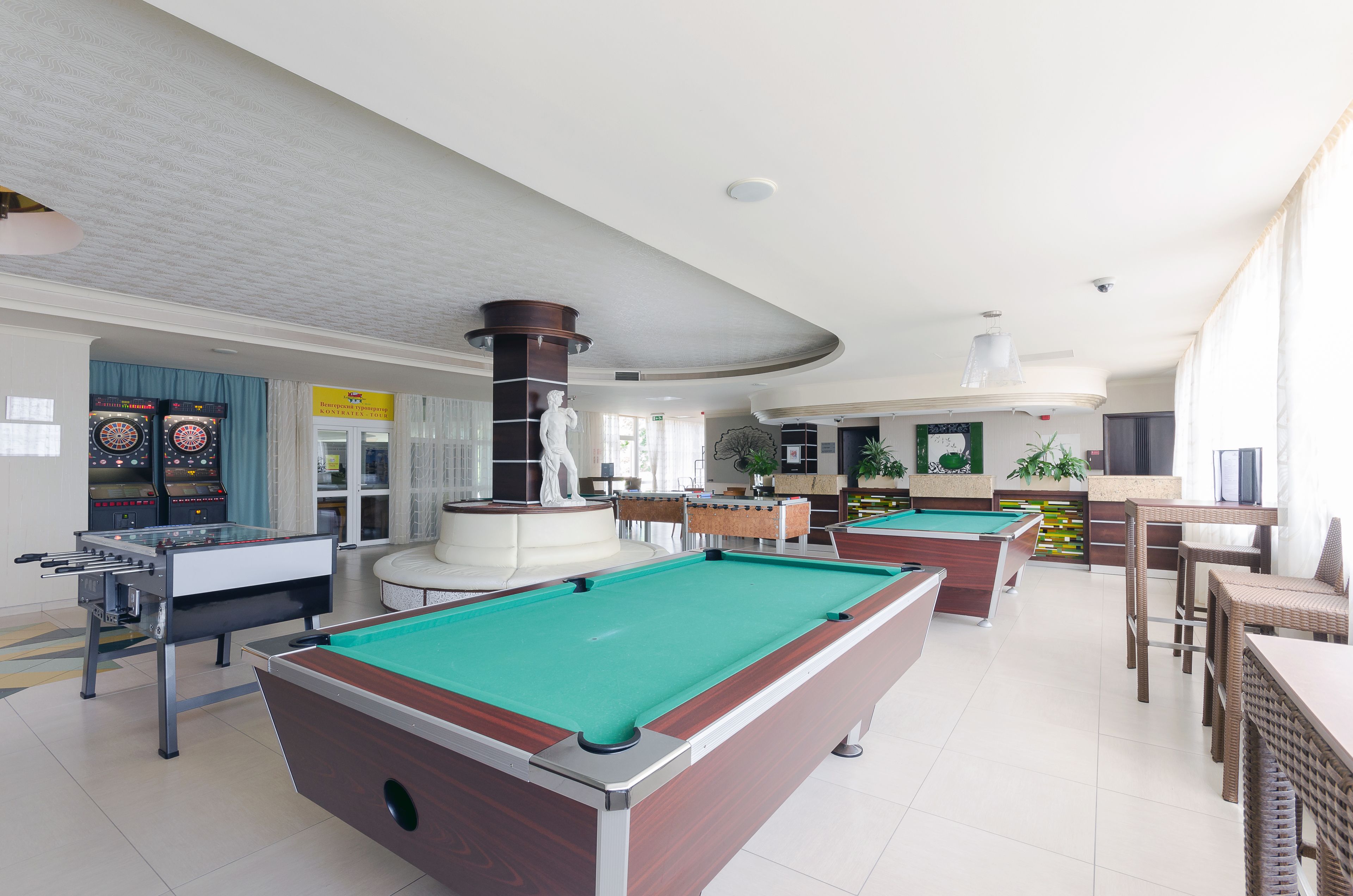 A pool table, foosball table, and billiard tables in a well-lit indoor recreational area with a modern design.