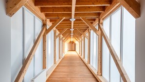 A corridor with wooden beams and large windows, leading to a bright interior space. - Hunguest Hotel Apollo (Hajduszoboszlo)