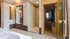 A modern bathroom with a large mirror, a bathtub, and a shower area. - Hunguest Hotel Apollo (Hajduszoboszlo)