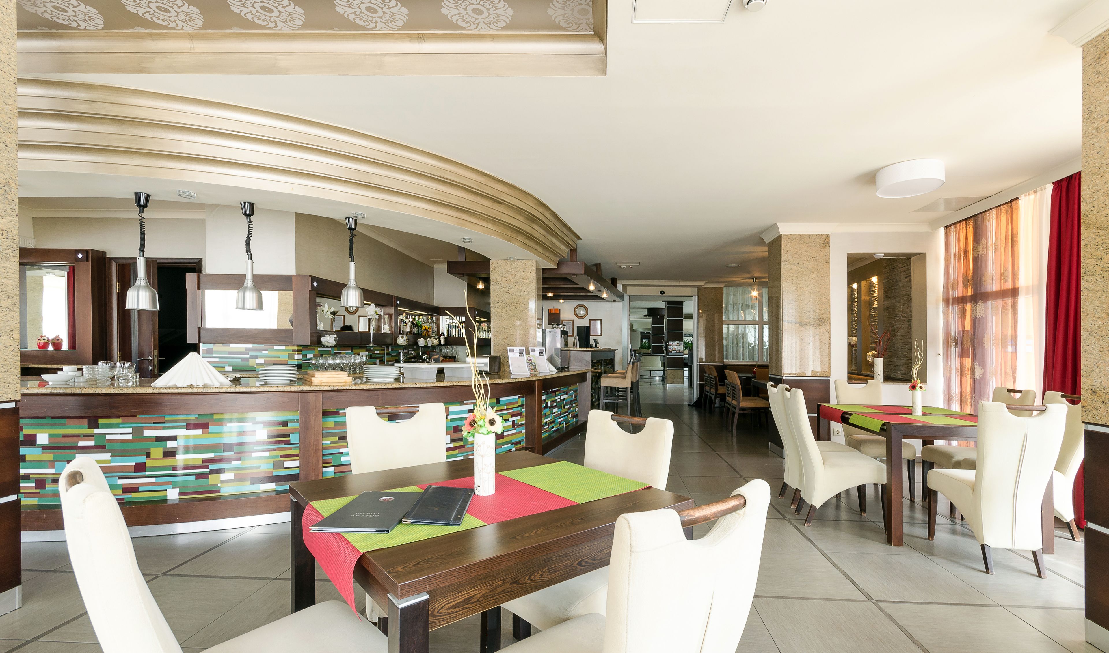 Un restaurante moderno con una barra curva, varias áreas de estar y una mezcla de mobiliario de madera y tapizado.