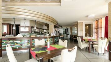Un restaurante moderno con una barra curva, varias áreas de estar y una mezcla de mobiliario de madera y tapizado.