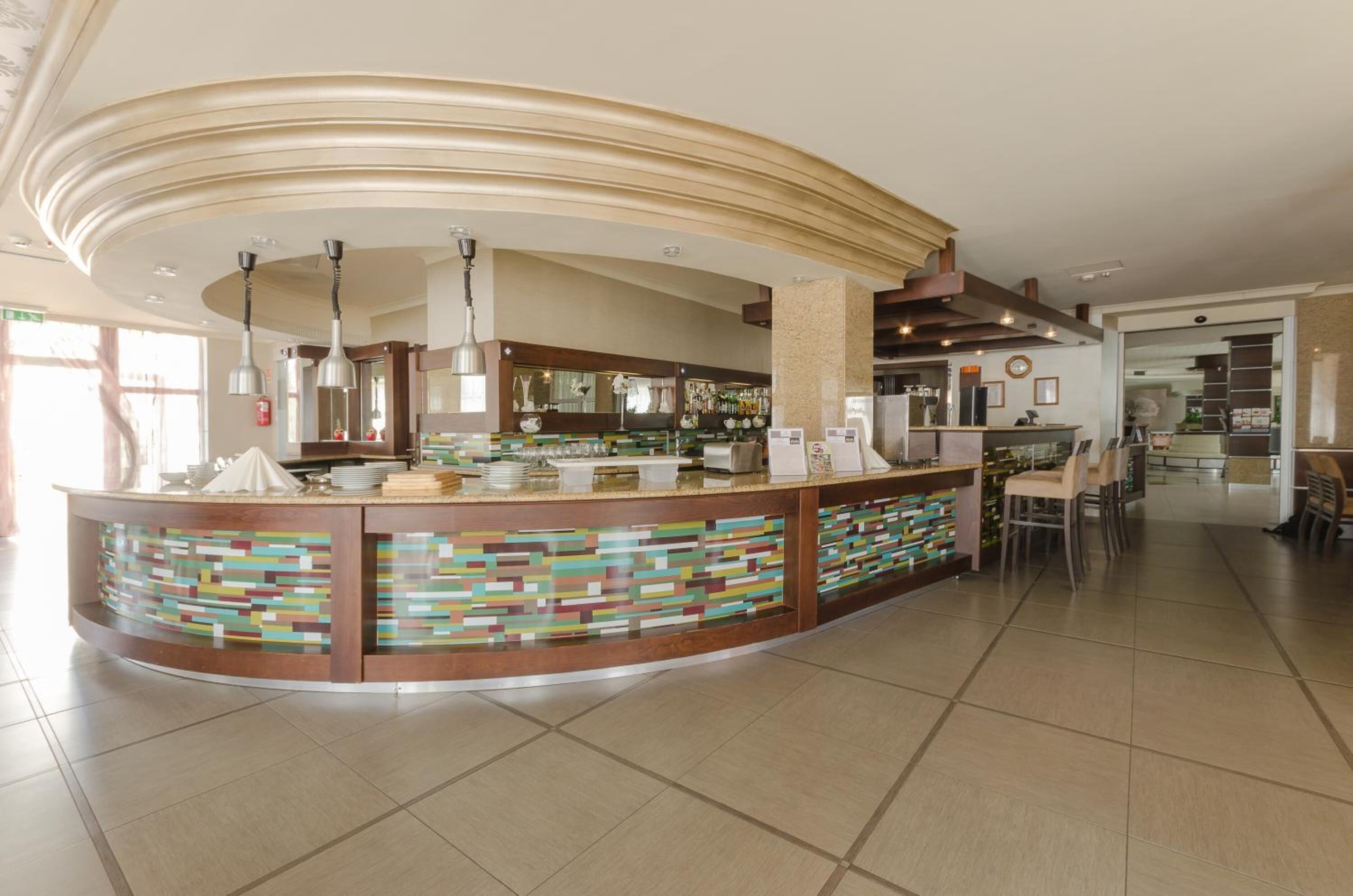 A modern bar area with a curved counter, multiple seating options, and a variety of bar amenities.