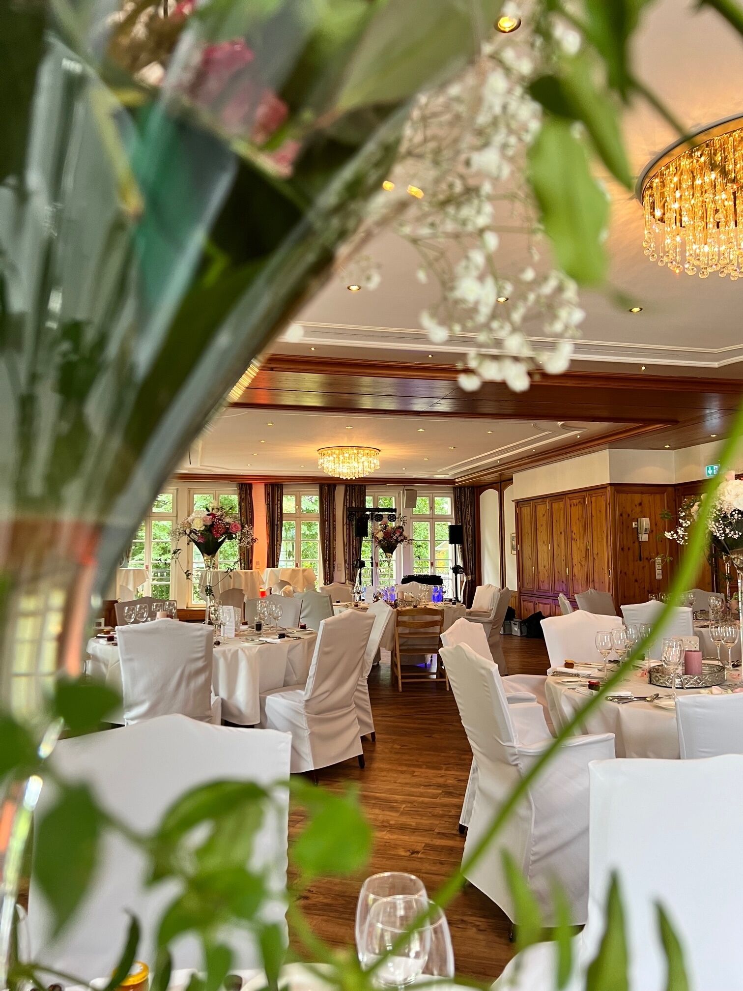 Een feestzaal met ronde tafels, witte tafellakens en stoelen.