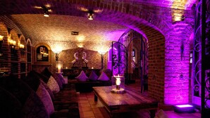 Une pièce chaleureuse et faiblement éclairée, avec des murs en briques, des meubles en bois et un éclairage violet.