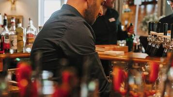 A bar area with shelves of liquor bottles and a bartender preparing drinks.