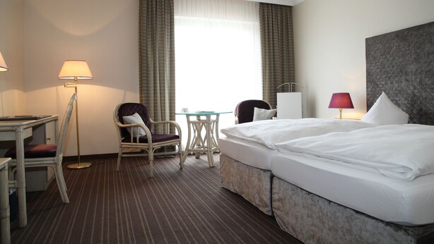 Ein Hotelzimmer mit einem Bett, zwei Stühlen, einem kleinen Tisch und einem Schreibtisch.