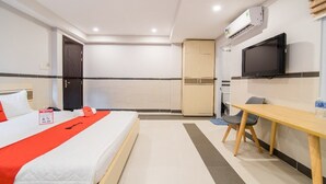 Una habitación de hotel con una cama, un escritorio, un televisor y un aire acondicionado.
