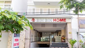 La entrada a Bin Bin Home, con un letrero, una escalera y un pequeño jardín.