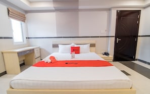 Une chambre d’hôtel avec un lit, une table de chevet et un bureau.
